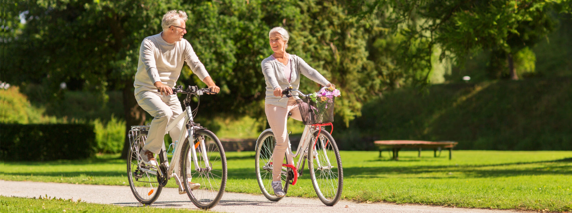 Traditional & Roth IRA Accounts - Elderly man & woman riding bikes in a park | Ozark Bank